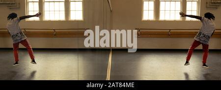 Dancer in Dance Studio Featuring a Full Length Mirror and Reflection with a Black African American Man Jumping. The image reflects the dance move. Stock Photo