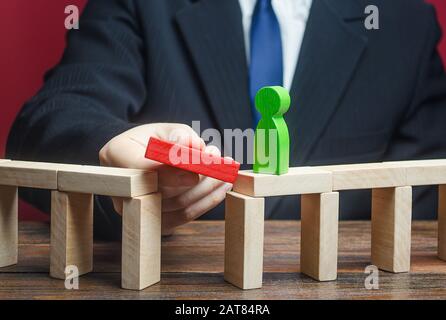 A businessman builds a path way for a green figure. Make a path to success, support and financial assistance. Career growth and professional developme Stock Photo