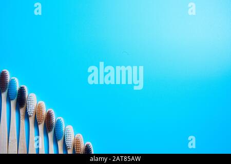Multi-colored wooden toothbrushes. Place for text on a blue background. Stock Photo