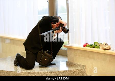Belarus, the city of Minsk, October 05, 2016. Photo exhibition in the library. The photographer takes a photo. A man with a camera photographs a flowe Stock Photo