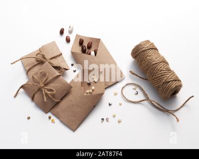 Heritage, heirloom garden seeds in home made brown paper packets, collected in the fall and ready for planting in spring, on white. Stock Photo