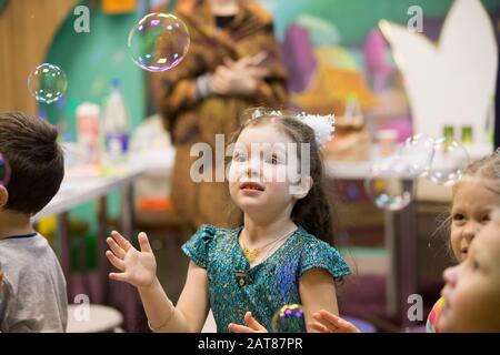 Children at the feast. Soap bubbles show. Children's party. To burst the soap bubble Stock Photo