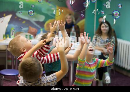 Children at the feast. Soap bubbles show. Children's party. To burst the soap bubble Stock Photo