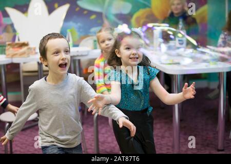 Children at the feast. Soap bubbles show. Children's party. To burst the soap bubble Stock Photo