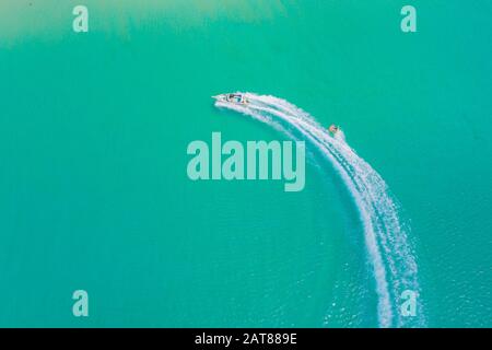 Aerial drone photo of extreme powerboat donut water-sports cruising in high speed in tropical turquoise bay. Thailand, Phuket, Kata beach Stock Photo