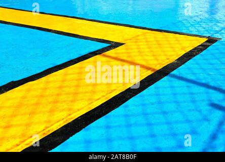 Black and yellow geometric lines are painted on a bright blue metal ship floor, serving as guides for passengers during emergency situations. Stock Photo