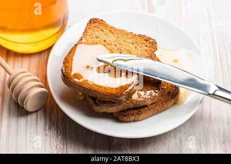 Spread honey on wholemeal rusks with knife. Stock Photo