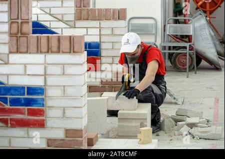 Young bricklayer performs a task of competition Stock Photo