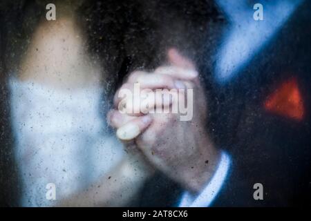 Close up through dirty window of of couple holding hands. Stock Photo