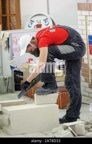 Young bricklayer performs a task of competition Stock Photo