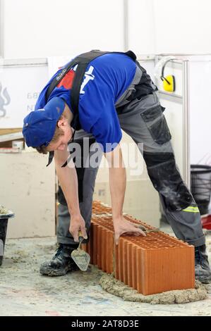 Young bricklayer performs a task of competition Stock Photo