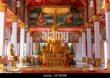 Wat Si Saket, a large golden Buddha statue and altar with offerings and wall murals, Vientiane, Laos Stock Photo