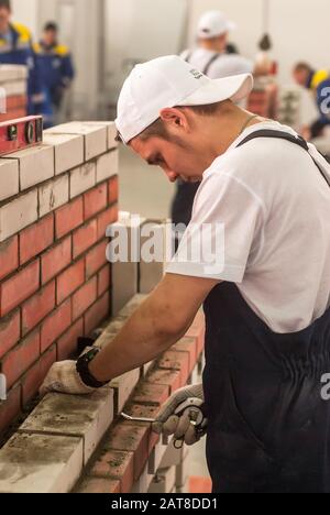 Young bricklayer performs a task of competition Stock Photo