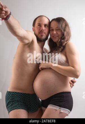 Beautiful pregnant woman and her handsome husband are kissing while spending time together in bed. Stock Photo