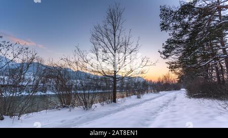 Tractor tracks in the snow, twilight over the snowy field, winter landscape. Stock Photo