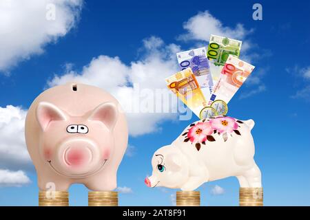 two piggybanks with banknotes on Euro coins in front of cloudy blue sky, composing Stock Photo