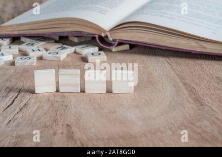 four blank cubes on a wooden table against old book Stock Photo