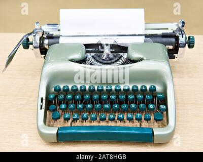 Green retro typewriter on wooden table Stock Photo