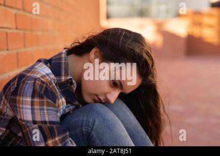 Teenage girl sitting in school grounds Stock Photo