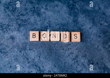 'Bonds' spelled out in wooden letter tiles on a dark rough background Stock Photo