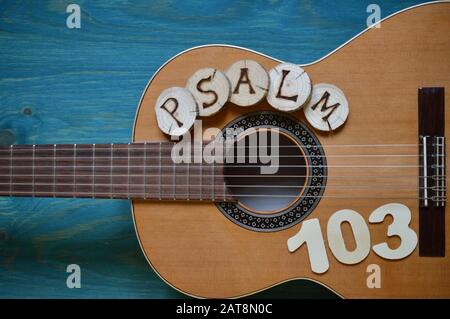 guitar on teal wooden background with wood pieces on it lettering the word: PSALM Stock Photo