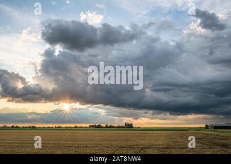 Sun tries to break through storm clouds over the countryside of the Netherlands Stock Photo