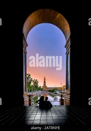 Silhouettes of young couple enjoying the sunset in the famous Spain Square (Plaza de Espana). Seville, Spain. Stock Photo