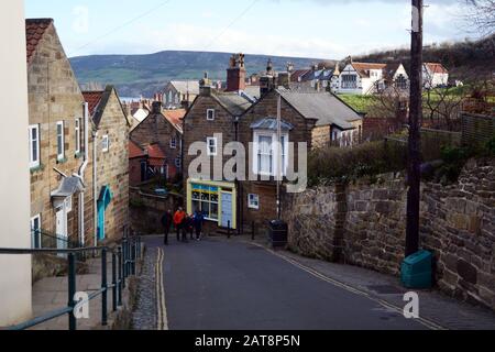 Tourists walking along a road in the town of Robin Hood's Bay, North York Moors National Park, Yorkshire, England, United Kingdom. Stock Photo