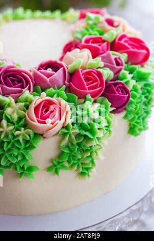 Bright festive white cake with bright flowers made of cream, a wedding cake, for a woman. Stock Photo