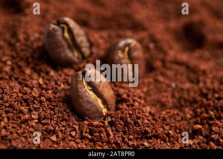 roasted beans lie on ground coffee. Close up. Stock Photo