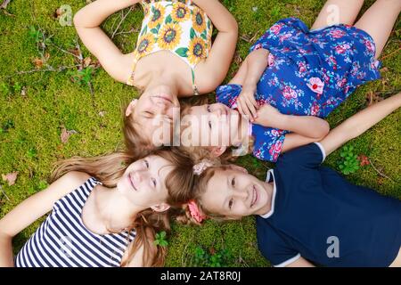 Girls of different age lying together on a moss in a summer forest enjoying summer holidays outdoor Stock Photo