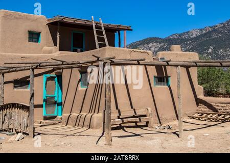 Adobe Mud multi-storied buildings in pueblo village that have been continuously inhabited for over 1000 years with New Mexico mountains in distance Stock Photo