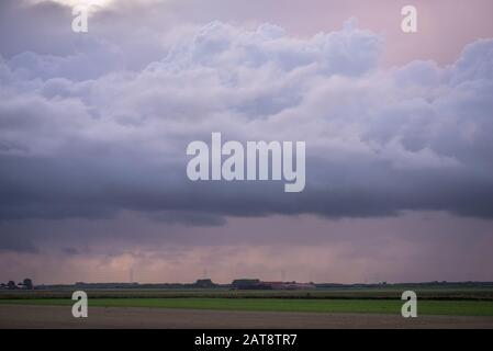 Stormclouds and falling rain at sunset Stock Photo