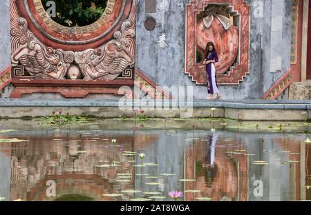 At Hoi An, Vietnam , on august 2019 -  Girl reflecting in the fountain of Tam Quan gate, or three-entrance gate, leading  to the old temple complex bu Stock Photo