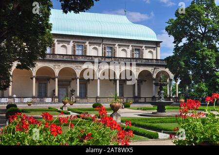 View of arched loggia of empty Anna's palace in Royal Garden with its Singing Fountain, statues and garden, red flowers and against vibrant blue sky a