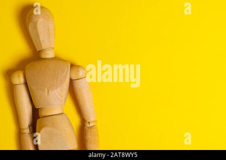 A wooden mannequin in a ballet pose, on it's base, on a white