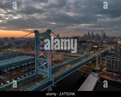 Philadelphia at night, aerial view of skzline at sunset with Benjamin Franklin Bridge and waterfront, skyscrapers dominating cityline against dramatic Stock Photo