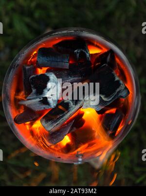 Burning coals. Decaying charcoal. Texture embers closeup. Burning coal. Glowing embers smoldering. Fire place with glowing coal. Live coal burning. Stock Photo