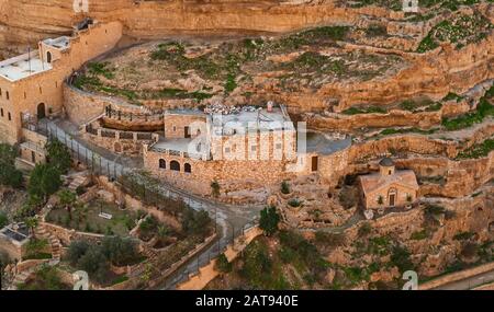 closeup of the east side of saint george's monastery and chapel in wadi qelt showing buildings carved into the limestone cliffs and caves of wadi qelt Stock Photo