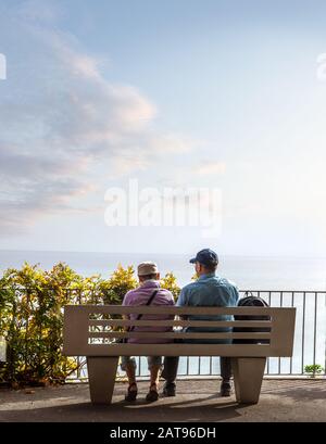 Rear view of senior couple sitting and look at the endless horizon Stock Photo
