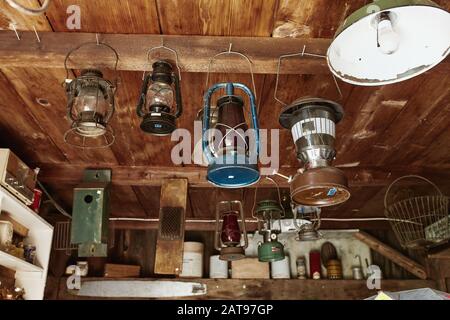 Vintage kerosene lanterns hanging from the ceiling of a wooden shack at an antique store. Maine, USA Stock Photo