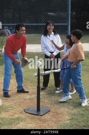 Austin, Texas: Vietnamese parents help son and daughter practice tee ball batting. ©Bob Daemmrich Stock Photo