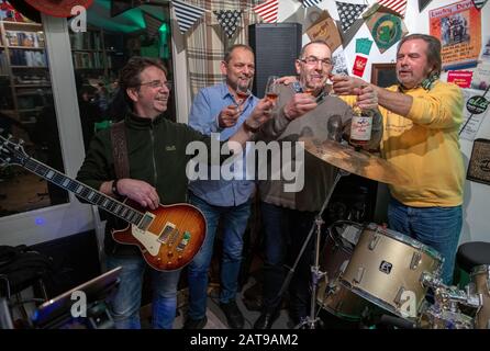 31 January 2020, Schleswig-Holstein, Klein Pampau: Iain Macnab (2nd from right), former mayor of the small community of Brunsmark near Mölln, toasts with his fellow musicians Sigi Krei (l), Peter Kruschel (2nd from left) and Wolle Flensky (r) with a whisky during the rehearsal of the band 'Lucky Devils'. The Scot Macnab has lived in Germany for over forty years and has been mayor of the town of 160 inhabitants for eleven years. With the brexite Macnab has to resign from his office as mayor and is also no longer allowed to participate in the municipal council. Photo: Jens Büttner/dpa-Zentralbil Stock Photo