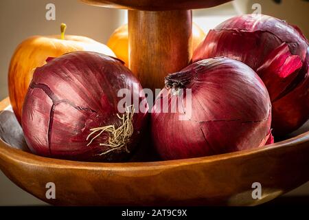 Red onions in wood bowl on sunny window sill Stock Photo