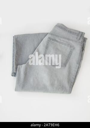 Pin striped gray pants isolated on light background.  Light gray denim trousers are folded in a flat lay still life for fashion. Stock Photo