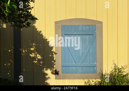 a yellow farm building with a blue barn door with deep shadows Stock Photo