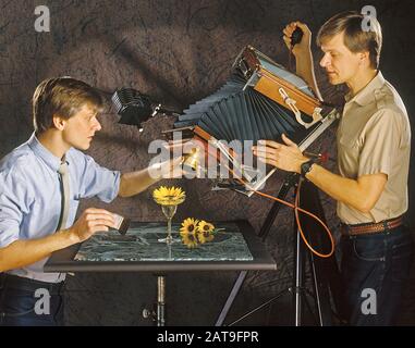 Two photographers using a Deardorff 8x10 inch format camera to photograph a flower on tabletop. Stock Photo