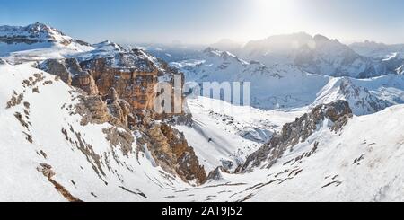 Winter panorama in Dolomites mountains, Italy - view from Pordoi peak (Sass Pordoi) towards an impressive ravine and the tall rock walls lit by the mo Stock Photo