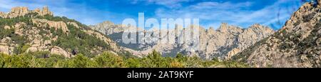 'La Pedriza' panoramic view an amazing rock maze inside a pine tree forest under a blue sky and clouds. Rocky area inside Guadarrama National Park Stock Photo