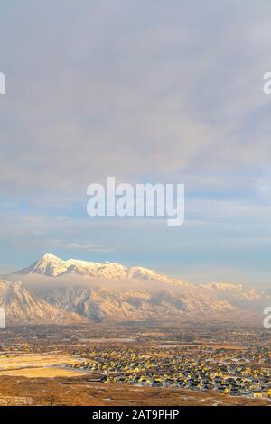 Mount Timpanogos and neighborhood houses under cloudy and foggy sky in winter Stock Photo
